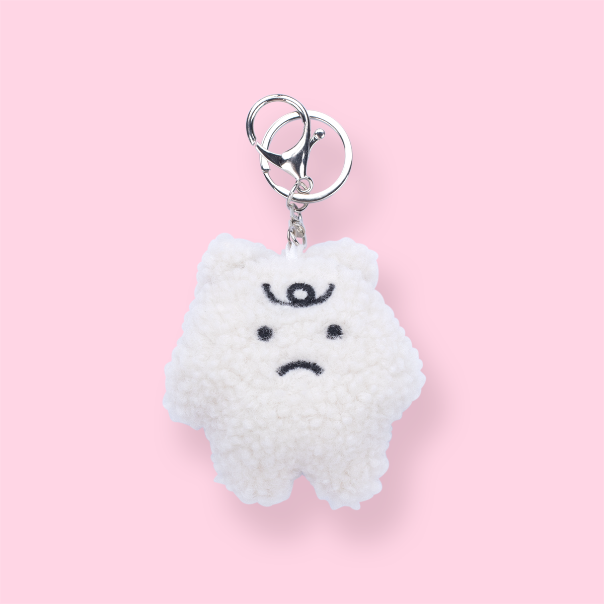 Fuzzy white bear keychain with a small frowning face and silver clasp
