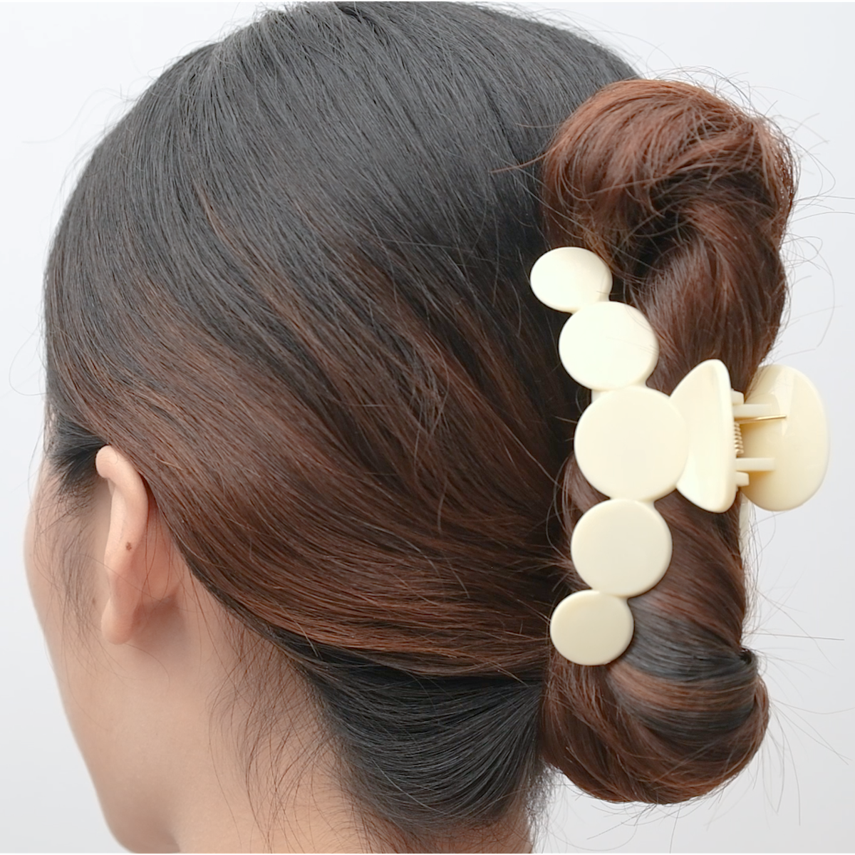 Beige rounded acrylic hair claw shown holding a bun