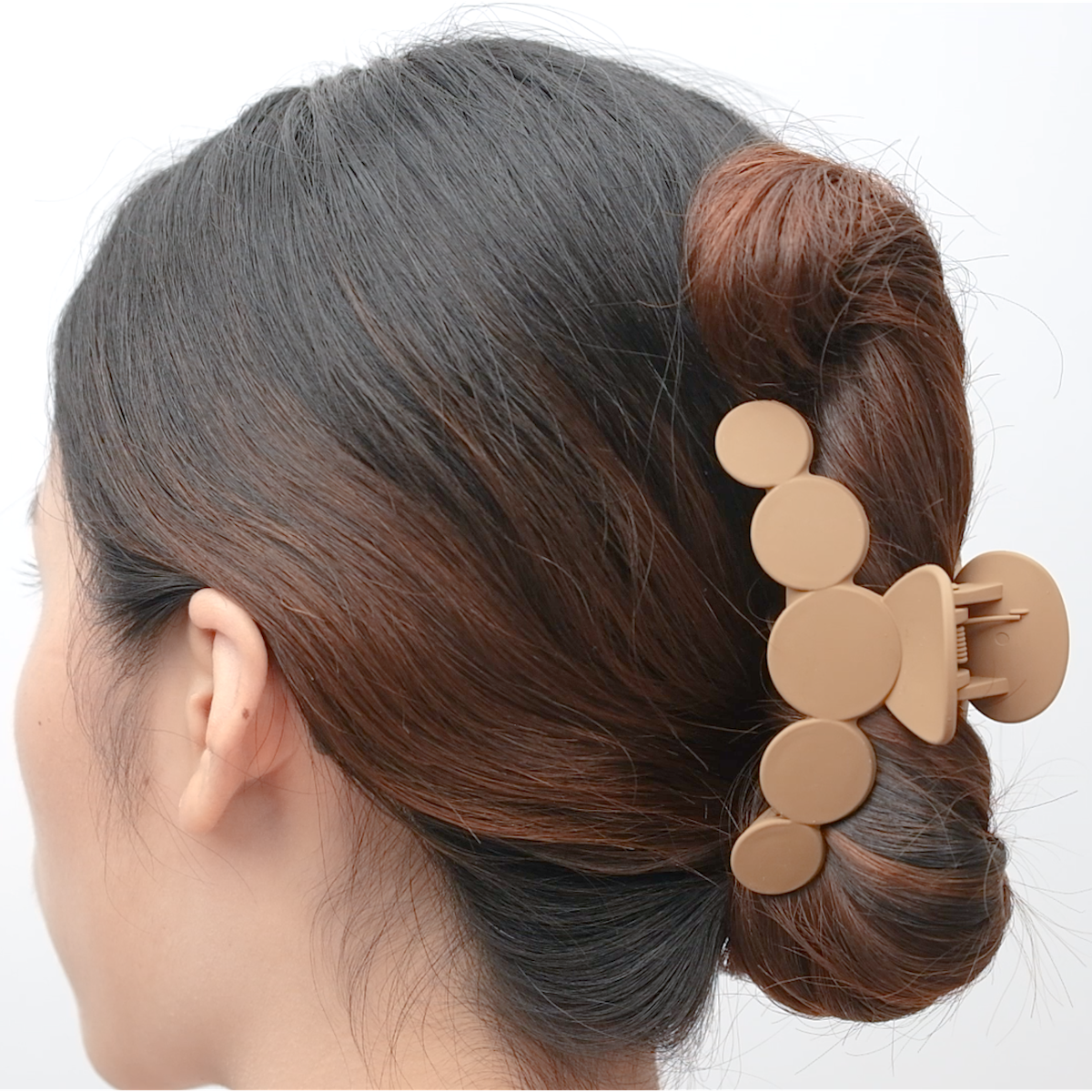Coffee-coloured rounded acrylic hair claw shown holding a bun